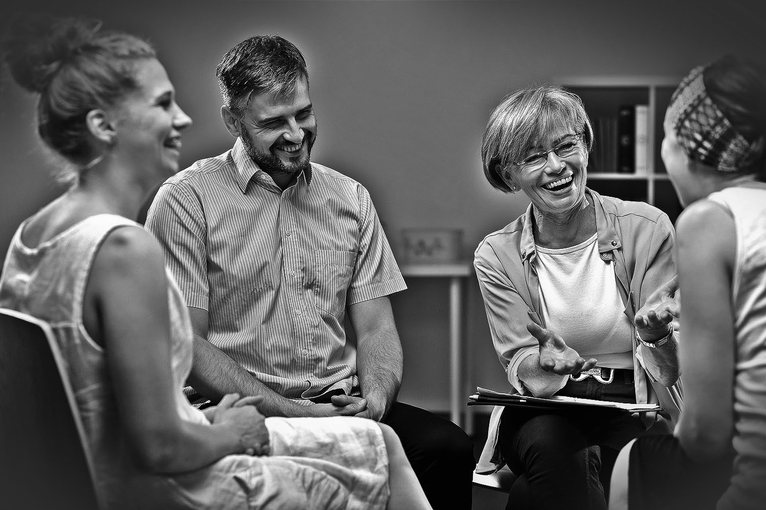 Four people sitting in a small circle, laughing mid-conversation